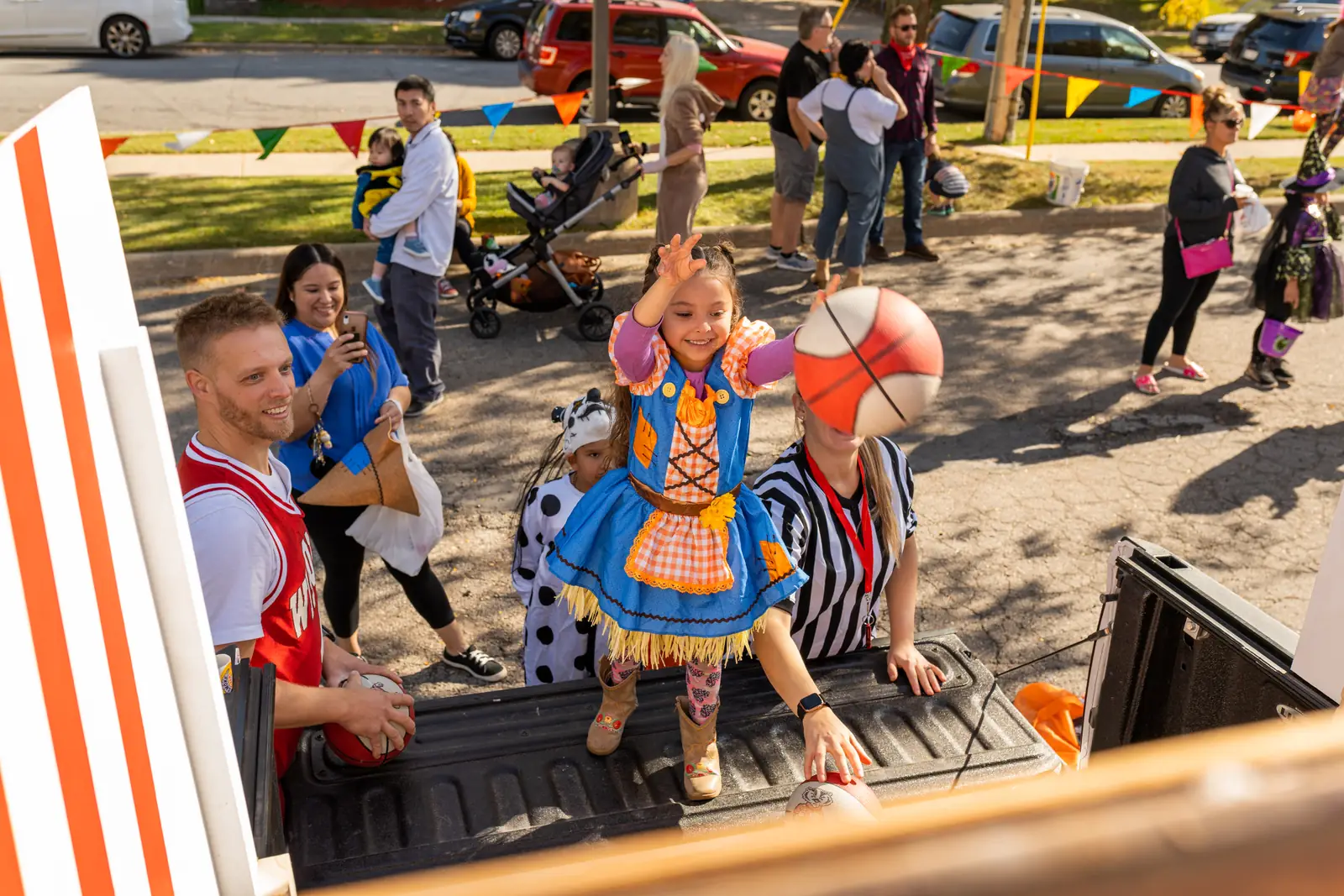 A girl in costume standing in a decorated truck bed at Trunk or Treat